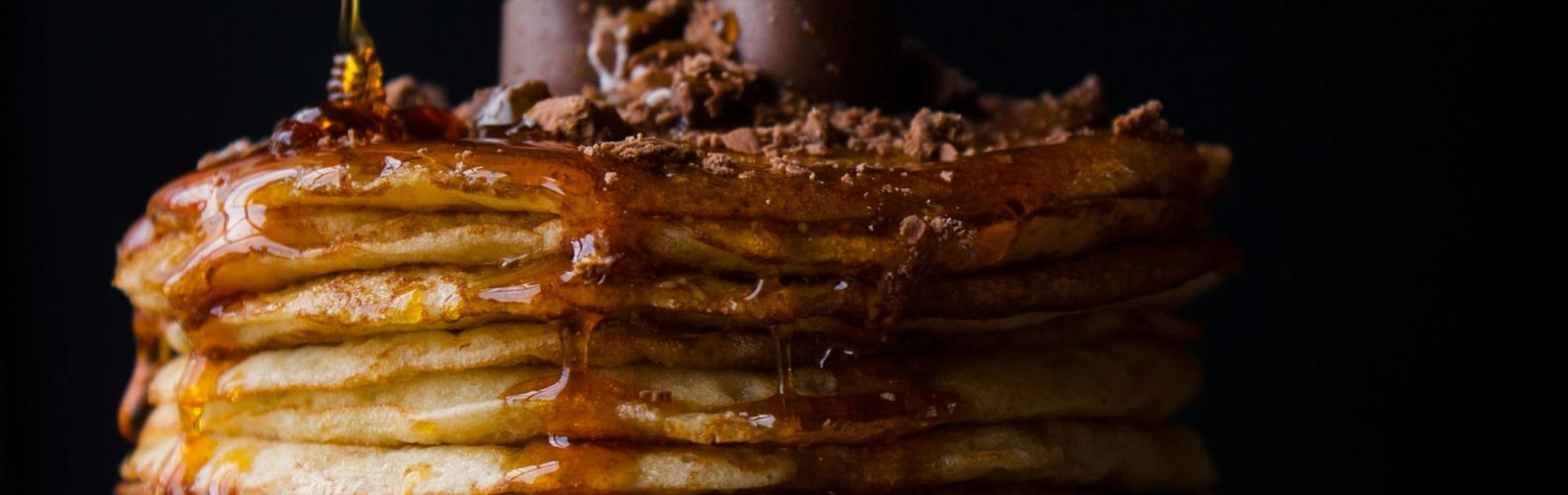 Mouthwatering stack of pancakes topped with chocolate and syrup. Perfect breakfast delight.